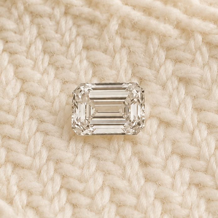 Emerald cut diamond on a textured beige fabric background